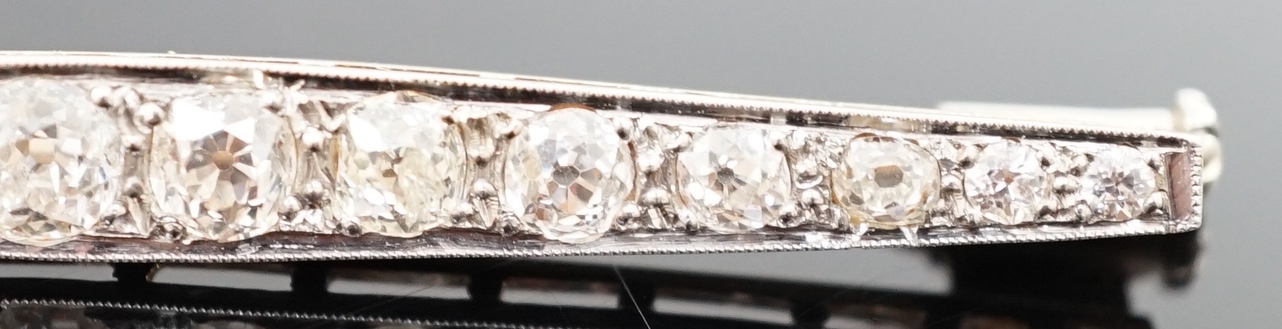 A 1920's gold, platinum and millegrain set graduated old round cut diamond bar brooch